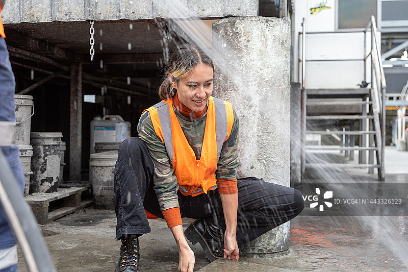 一名女工正准备清洗混凝土制造厂的一片区域图片素材