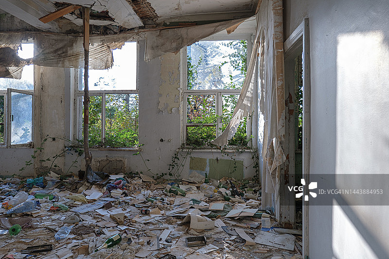 废弃的建筑。窗户上的碎玻璃。把旧文件撒在地板上。被遗弃的地方。图片素材
