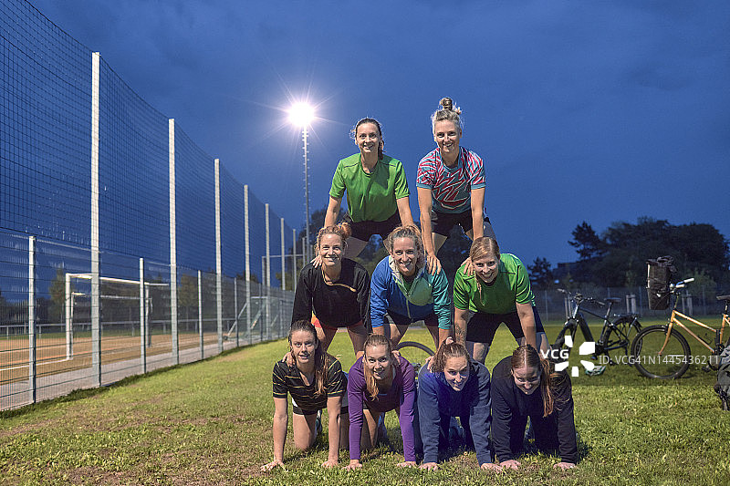 女子橄榄球队在晚上的运动场上建造了一个人体金字塔图片素材