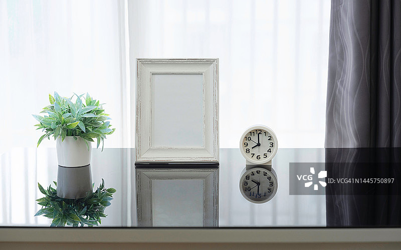室内海报模拟与垂直框架和植物花瓶在白色的墙壁背景。客厅的室内设计，白色的架子上有白色的模拟相框，花盆里有美丽的植物。图片素材