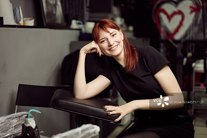 快乐的女纹身师坐在工作场所的肖像图片素材
