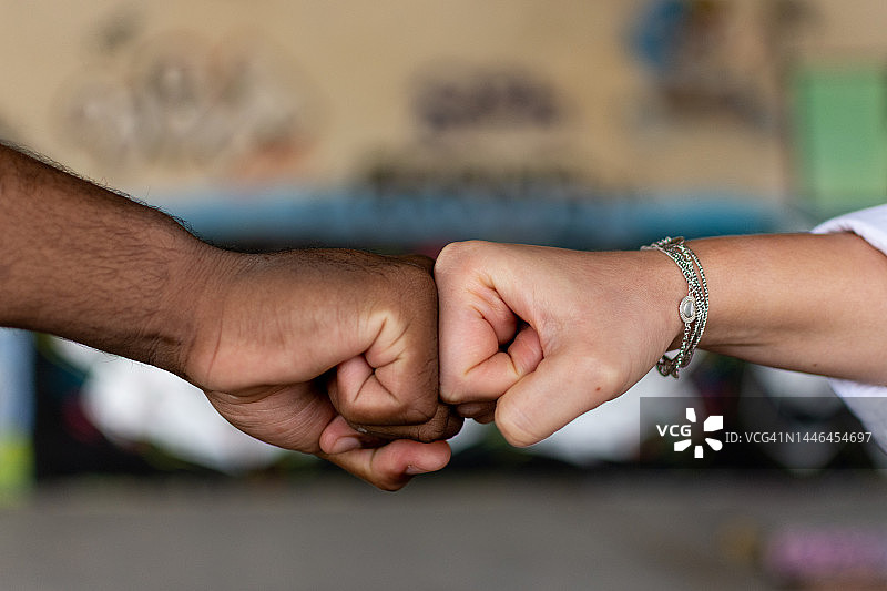 黑人和白人女人握紧拳头。联盟的概念。阻止种族主义。涂鸦墙背景。图片素材