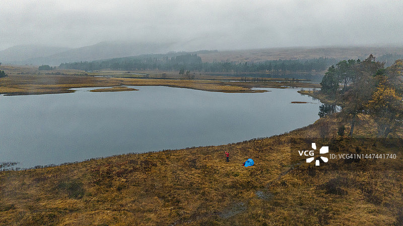 一名成年男子在苏格兰的一个湖边露营时，正在欣赏美丽的雾霭。图片素材