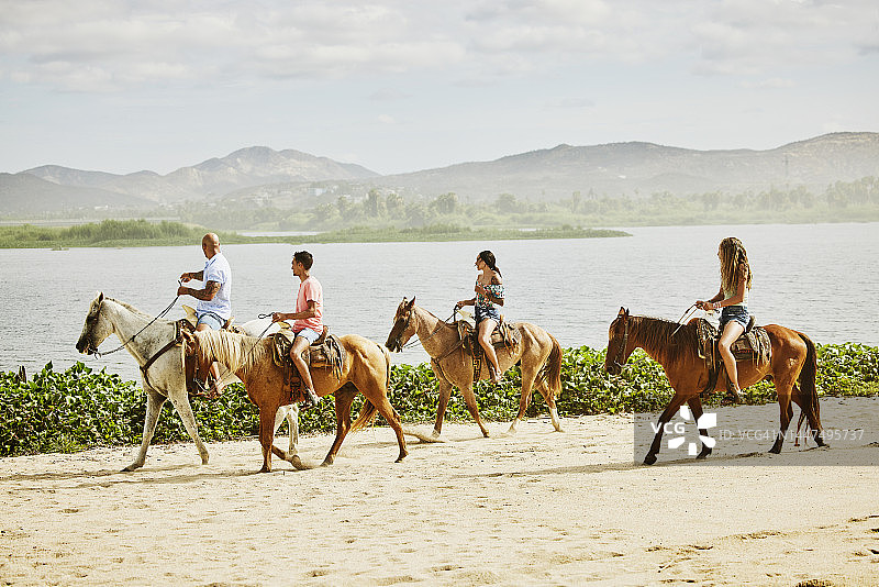 家庭度假期间在热带海滩骑马的广角镜头图片素材