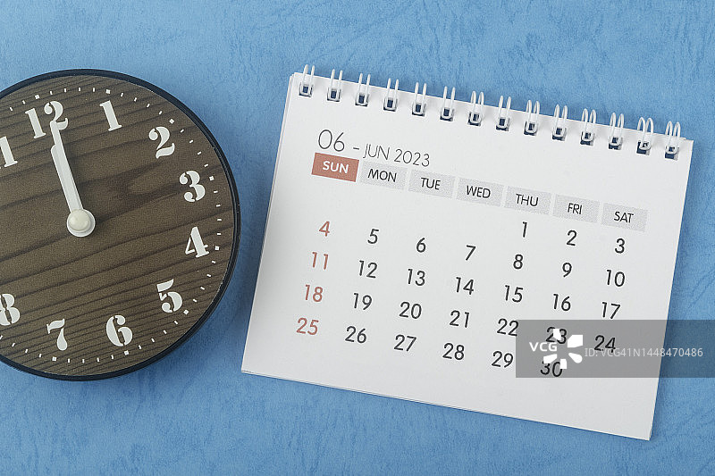 日历台2023:六月是组织者用蓝色纸背景的时钟来计划和截止日期的月份。图片素材