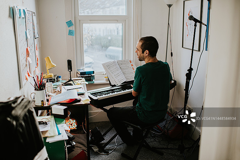 一个男人在一个小小的创意空间里弹奏键盘，唱歌图片素材