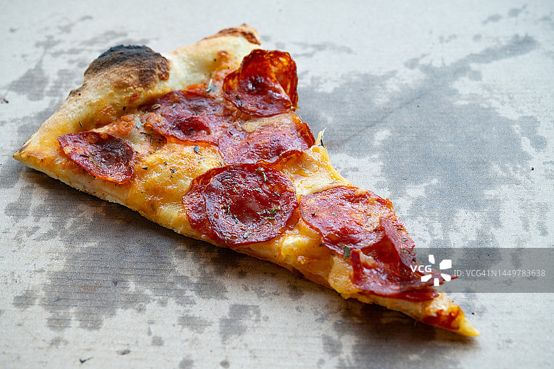 美味的意大利披萨，披萨盒和送货盒，在披萨店的桌子上。切片披萨片配番茄，意大利辣香肠和奶酪。不健康的生活方式，暴饮暴食，垃圾食品，快餐。送货上门或上班。图片素材