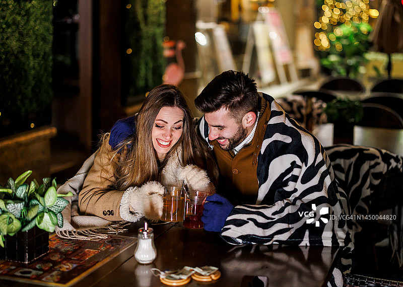 美丽时尚的情侣在一个寒冷的日子里坐在餐厅里喝热茶。图片素材