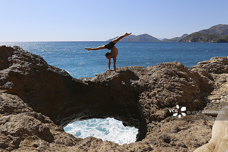 运动员在海边的岩石上做体操图片素材