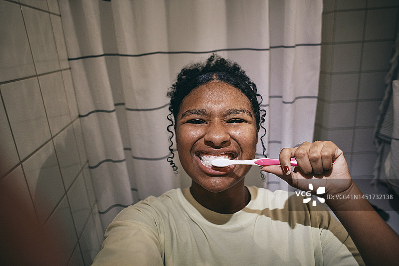 十几岁的女孩在家里的浴室里刷牙时自拍的照片图片素材