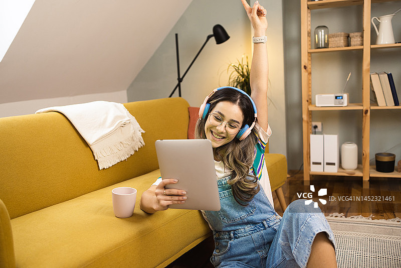 一个快乐的女孩使用平板电脑和跳舞与她最喜欢的音乐的肖像图片素材