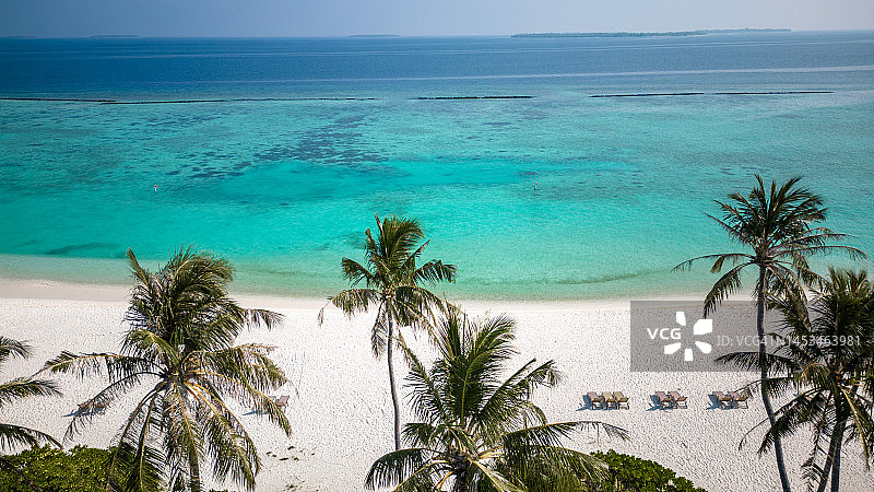 马尔代夫酒店泻湖和海滩在热带岛屿度假村的太阳椅和棕榈树图片素材