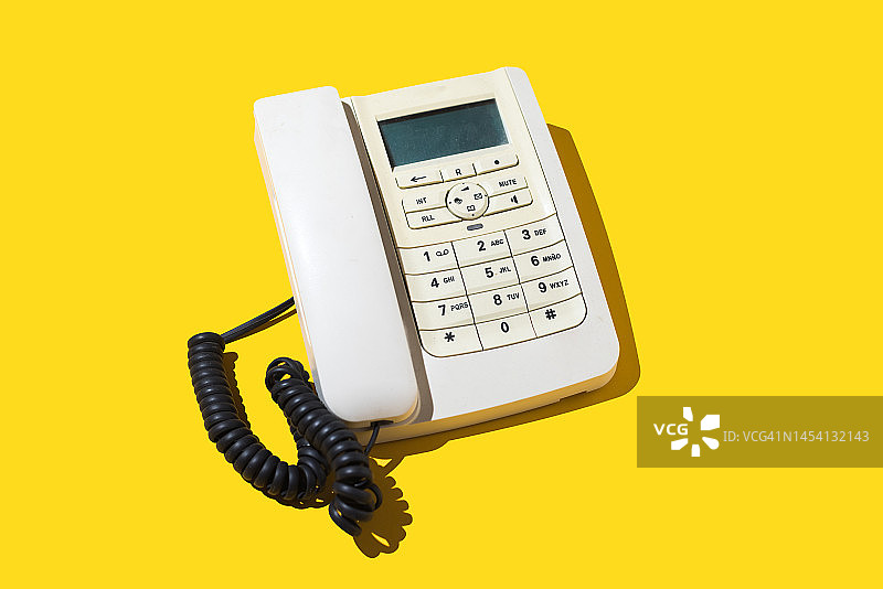白色复古电话，带电缆，黄色背景。旧的概念，电话，固定电话，通话，远程，听，总机和客户服务。图片素材