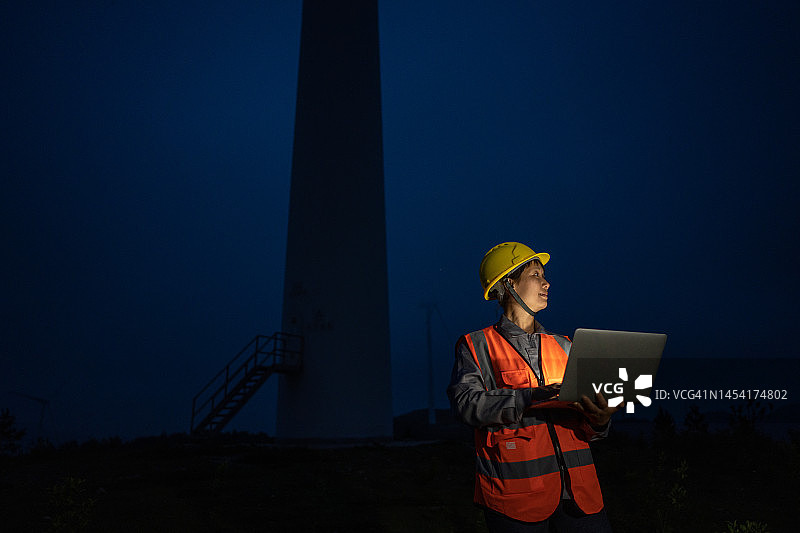一名女工人晚上在风力发电场的电脑前工作图片素材