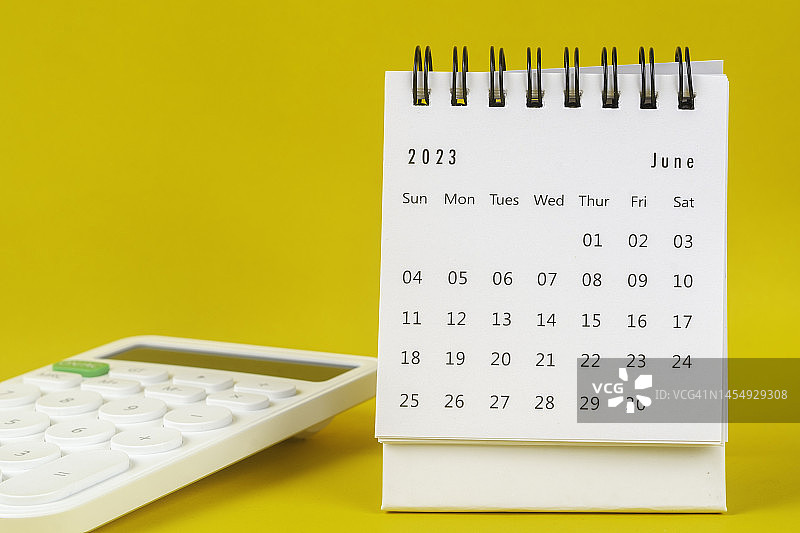 2023日历台:六月是组织者用黄色纸张背景下的白色计算器来计划和截止日期的月份。图片素材