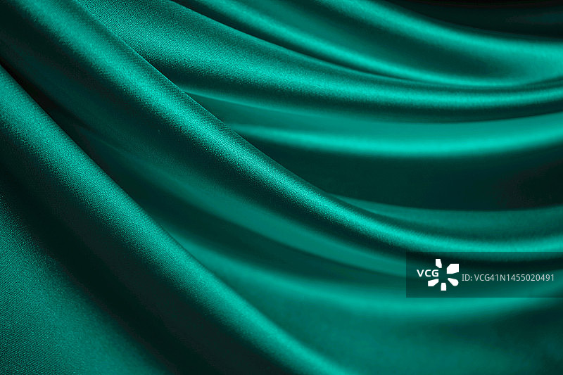 蓝绿丝缎。翡翠窗帘。布料。闪亮的织物。优雅的背景。图片素材