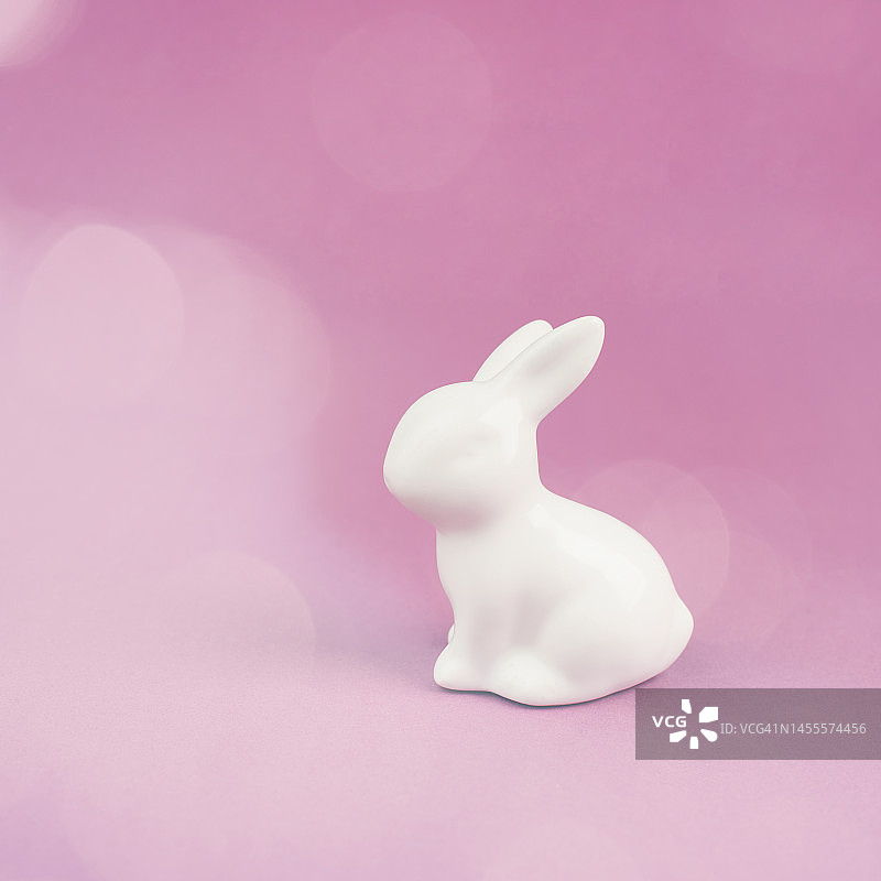 复活节兔子或兔子坐在粉红色粉彩颜色的背景，春节贺卡，散景光图片素材