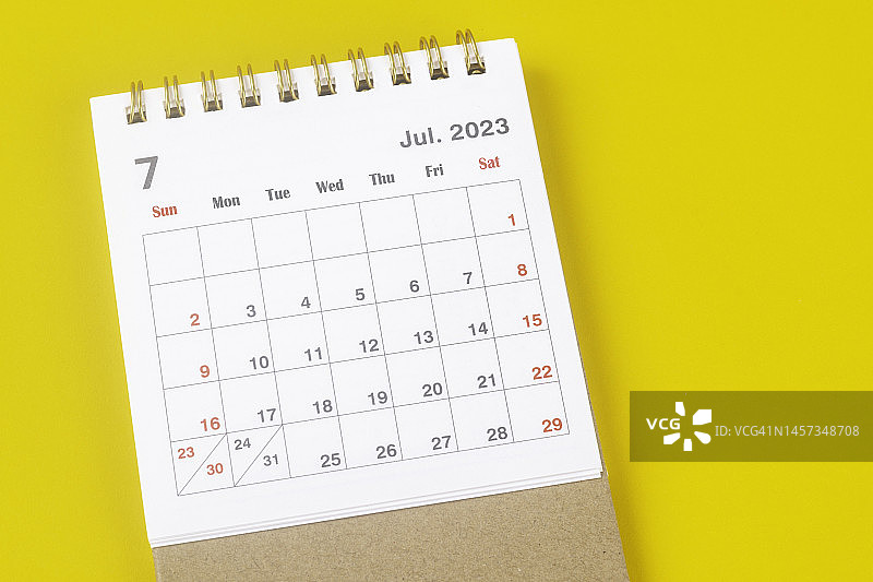 日历台2023:7月是组织者以黄色纸张为背景进行计划和截止日期的月份。图片素材