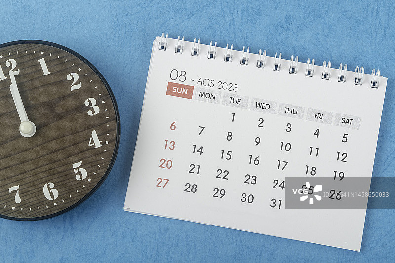 2023日历台:8月是组织者用蓝色纸背景的时钟来计划和截止日期的月份。图片素材