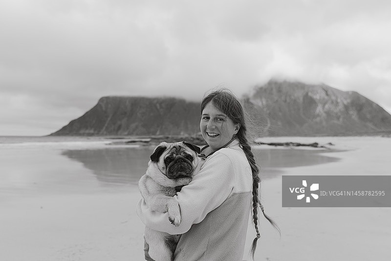 快乐的女人和狗的肖像在罗浮敦群岛的山海滩图片素材
