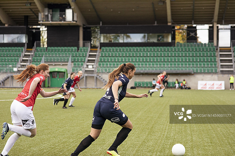 女球员在体育场比赛中带着足球奔跑图片素材