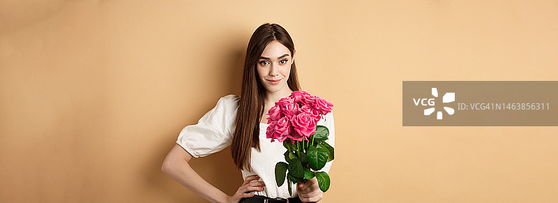 情人节美丽的女朋友捧着粉红色的玫瑰看着图片素材