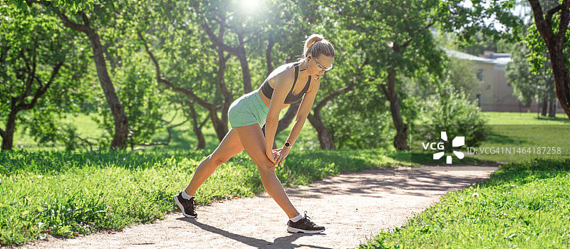 俄罗斯，一个中年白人妇女在阳光明媚的夏天早晨在公园里锻炼身体图片素材