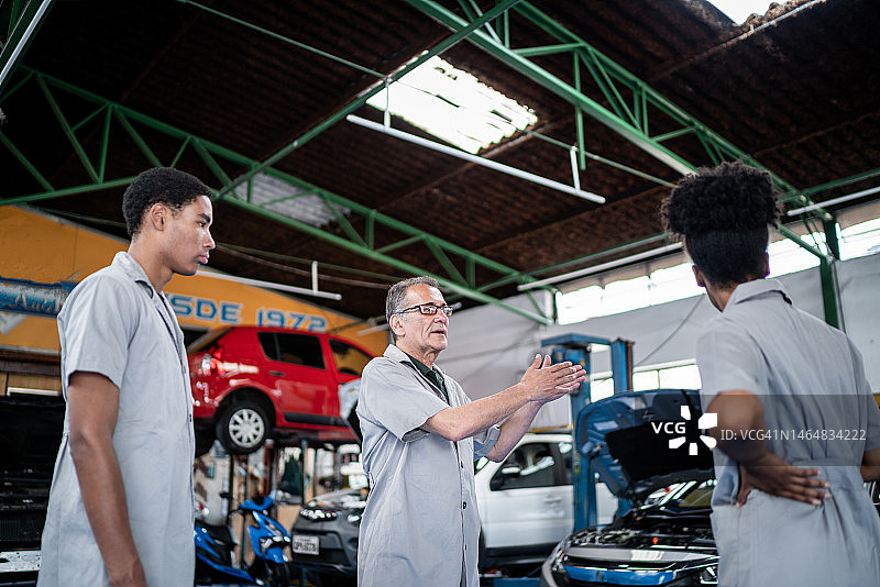 一个汽车修理工在修理厂和他的助手聊天图片素材