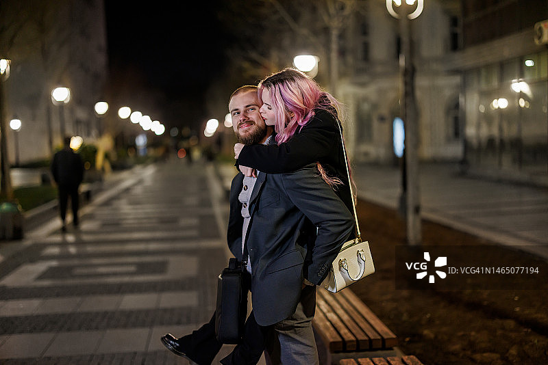 一对快乐的夫妇在夜晚走在市中心的肖像。图片素材