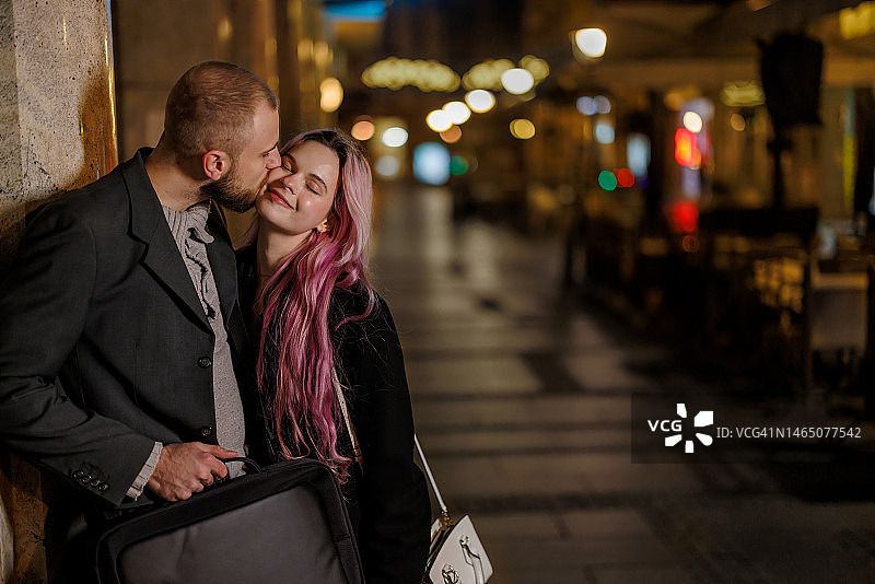 一对快乐的夫妇在夜晚走在市中心的肖像。图片素材