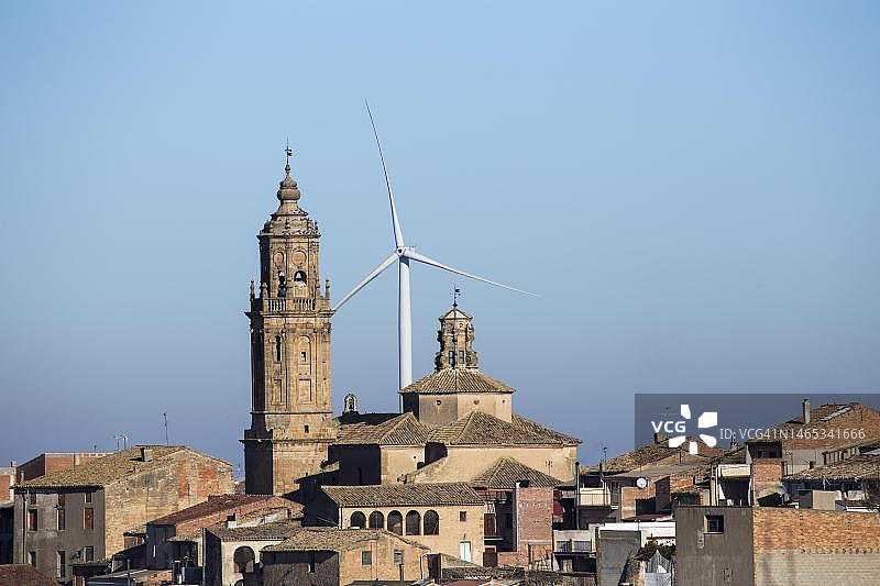 风电场，在它前面的一个古老的小镇教堂塔，加泰罗尼亚，西班牙图片素材