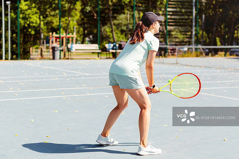 美丽的年轻女运动员，专业网球运动员与球拍练习在夏天的红土网球场图片素材