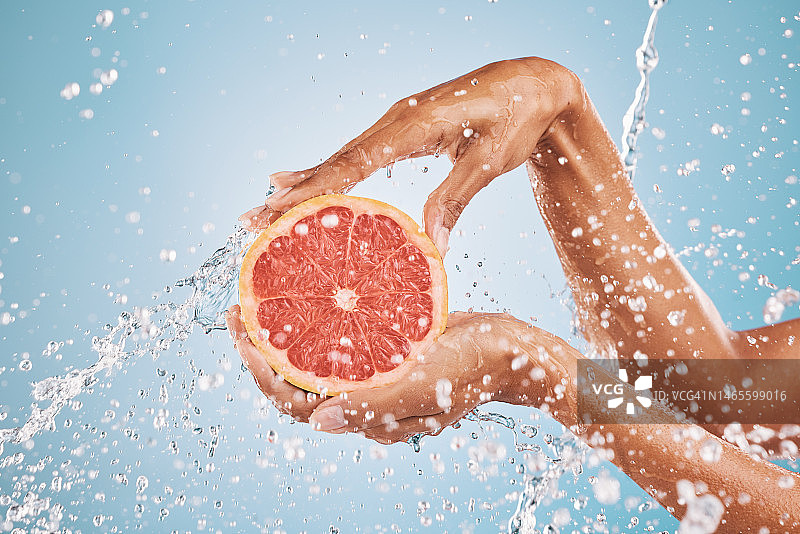 手部、水泼柚子美容护肤为维生素c营养，柑橘保健治疗和自然养生。健康的皮肤卫生，广告补水和蓝色的工作室背景图片素材