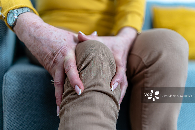 近距离观察一位因慢性疼痛而抱着膝盖的不认识的老年妇女。图片素材