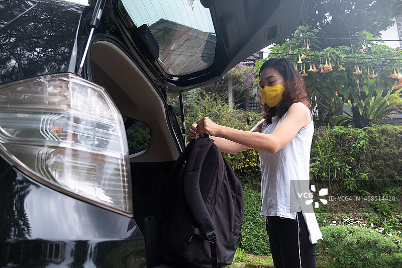 亚洲女子从汽车后备箱里拿出背包图片素材