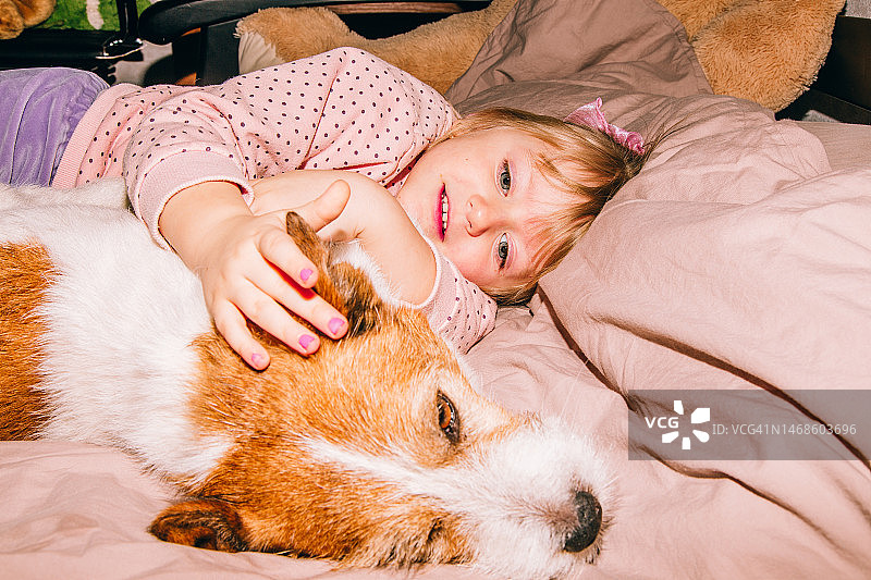 可爱的小女孩在床上抱狗图片素材