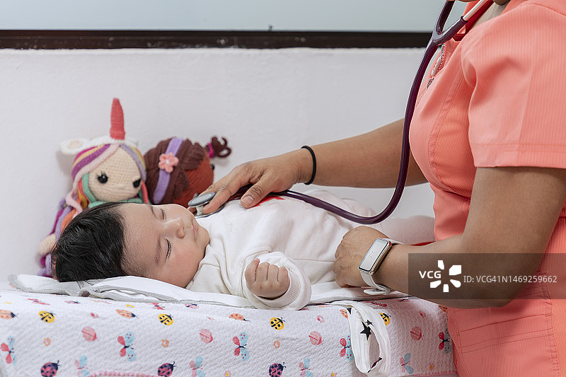 医生的手拿着听诊器，听着婴儿的心跳图片素材