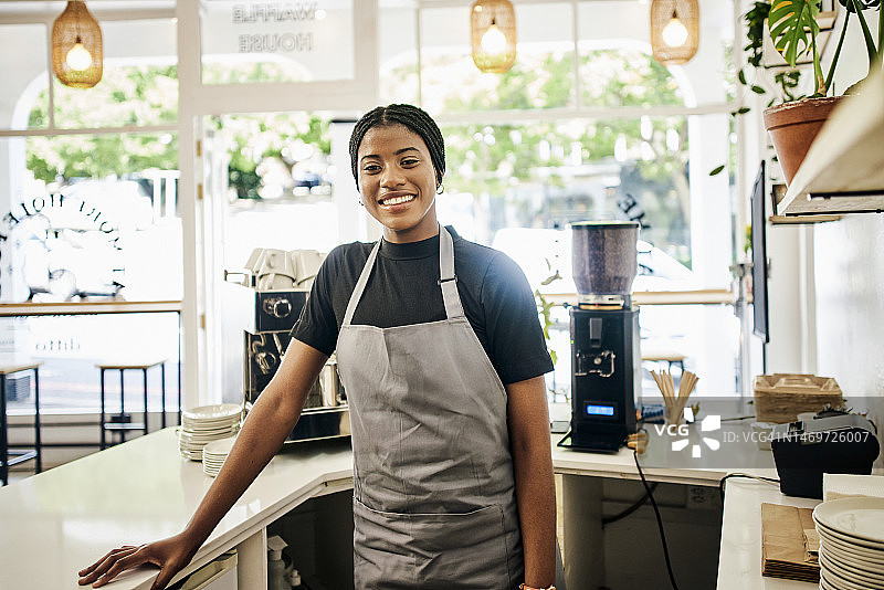 咖啡馆，肖像和黑人妇女或咖啡师在小企业创业，服务工作者或服务员微笑。咖啡店的年轻员工、员工或收银员对职业目标、门店或零售增长感到满意图片素材