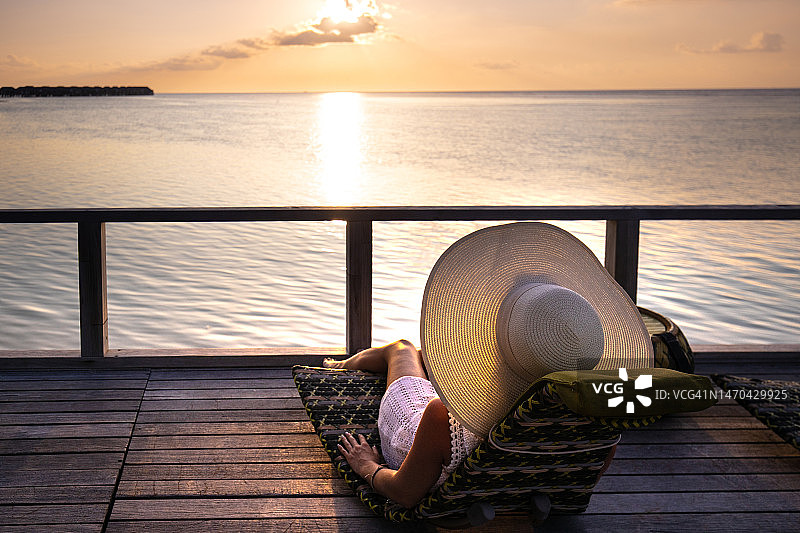 一个女人在日落时在院子里放松的后视图。图片素材