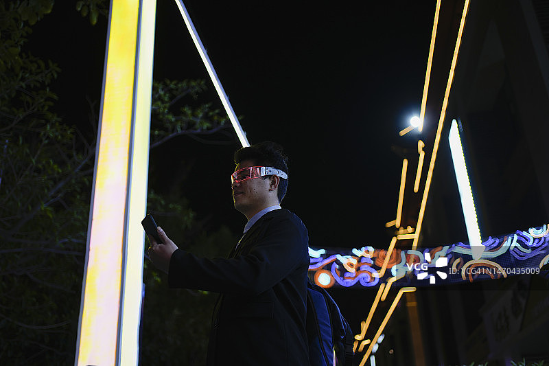 一名戴着智能眼镜的男子在夜间使用手机图片素材