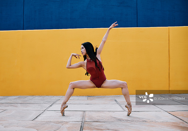 芭蕾舞演员在户外表演时踮着脚尖做下蹲。图片素材