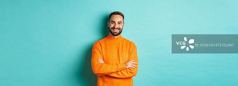 帅气的大胡子男模穿着橙色毛衣，看起来自信又图片素材
