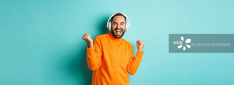 快乐的成年男子穿着橙色毛衣，抬头听着音乐图片素材