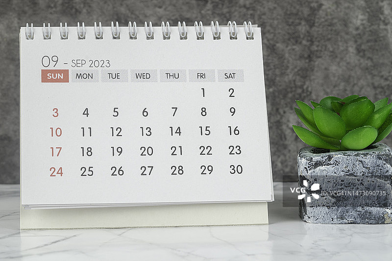 日历桌2023:9月是组织者计划和截止日期的月份，在混凝土墙背景下放置室内植物。图片素材