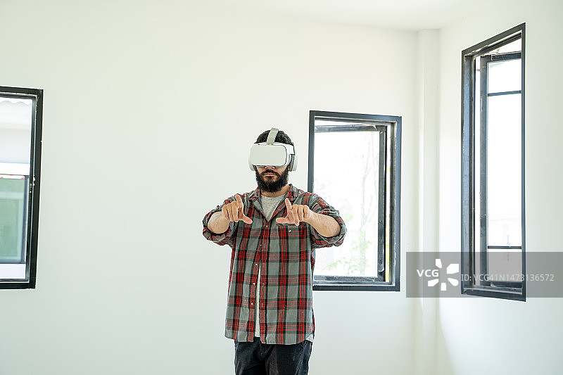 男子在家中使用VR眼镜。图片素材