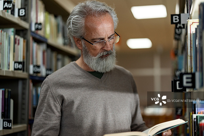 白人退休男子在市图书馆读书图片素材