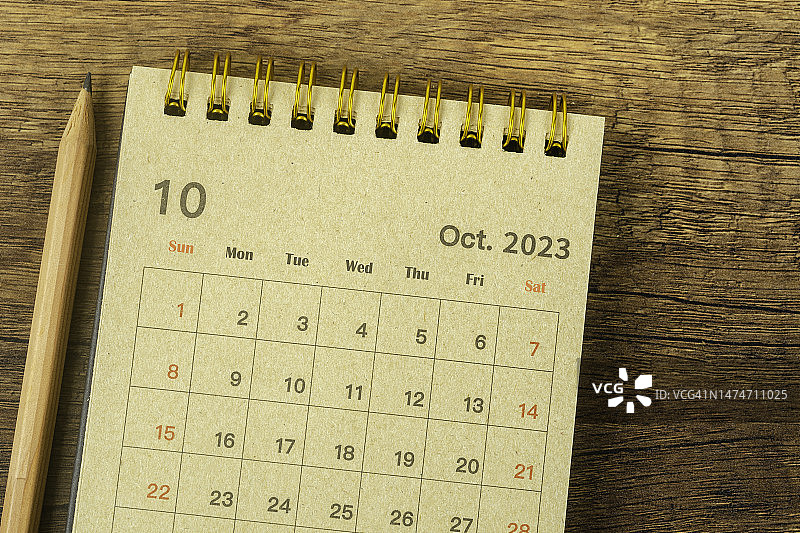 日历桌2023:10月是组织者用铅笔在木制背景上制定计划和截止日期的月份。图片素材