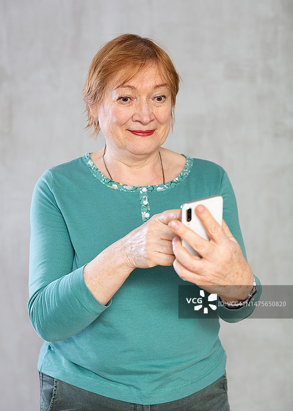 积极感兴趣的老年妇女看着手机图片素材