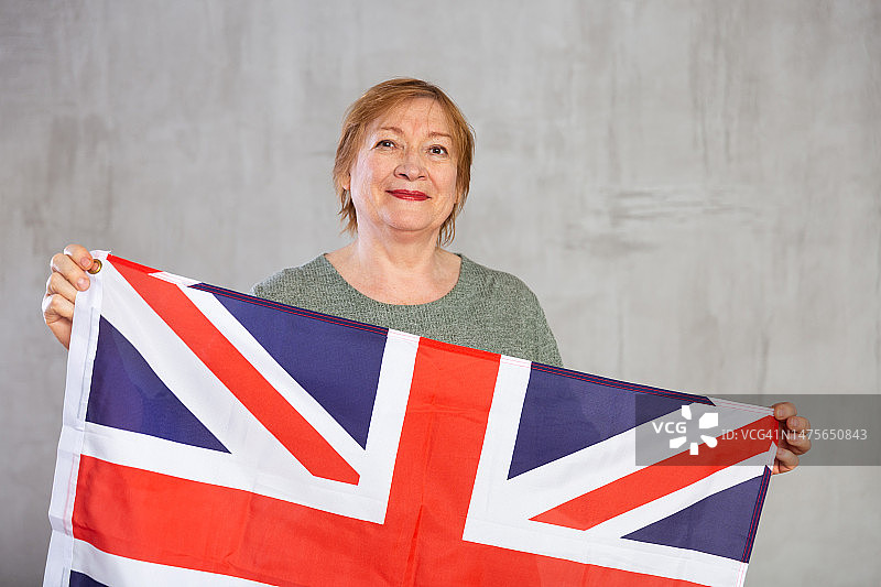 快乐的高级妇女自信地站在英国国旗图片素材
