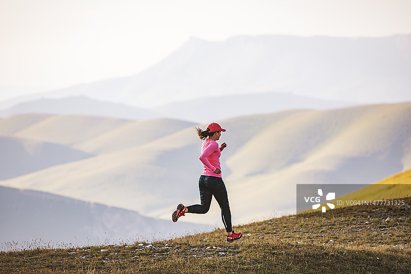 年轻的成年女子在日落时在山上跑步图片素材